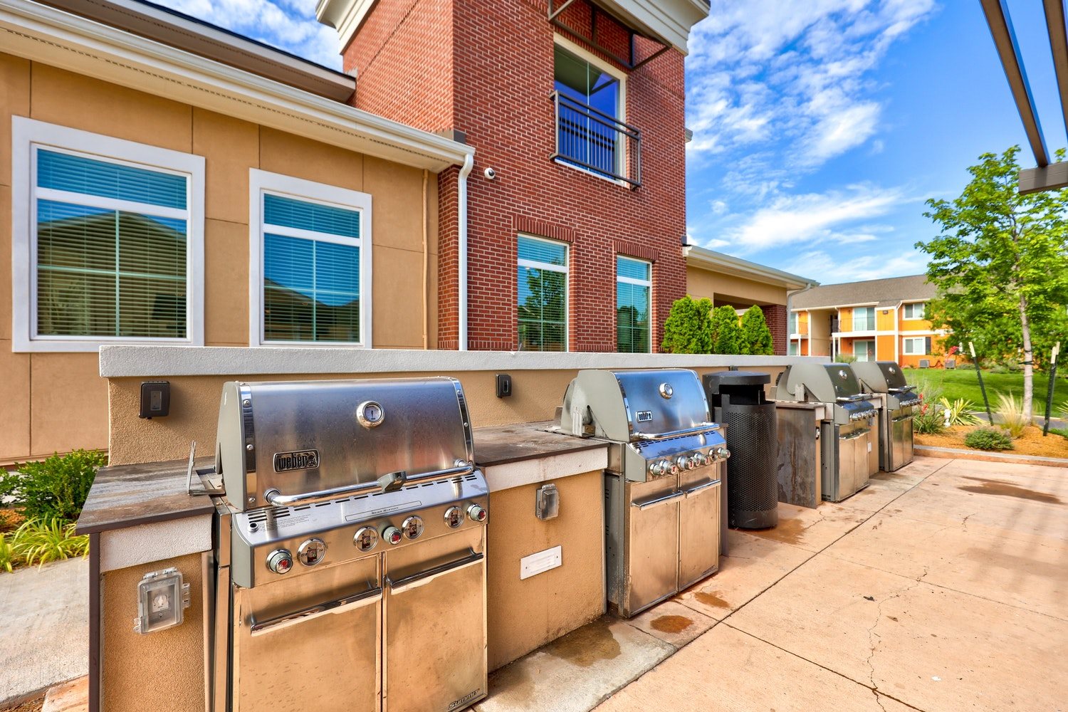 A row of outdoor grills are lined up on a sidewalk.